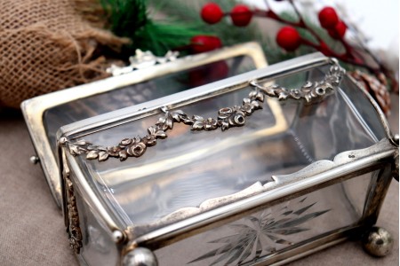 Guarda joias em vidro com estrutura em prata com aplicações e cartela para monograma, perlado e assente em quatro pés em formato esférico.